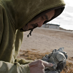 photo of Inuit man carving a small stone polar bear from rock